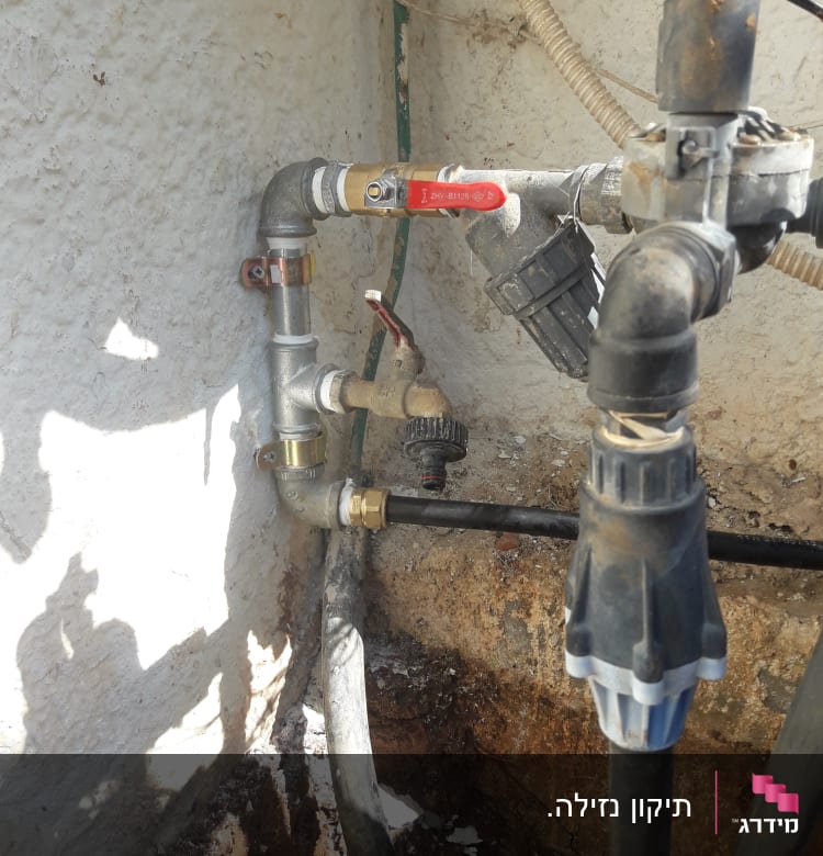 צינורות מים עם ברזים ומחברים על קיר חיצוני